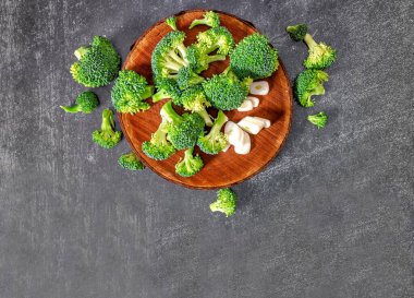 Green broccoli and garlic - still life image of food background. Top view. Wooden natural round stand