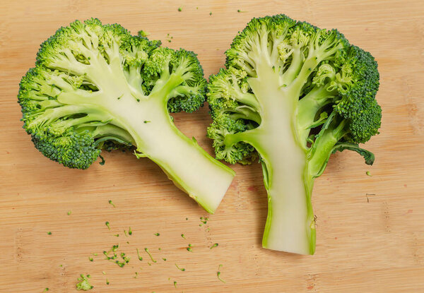 Two halves of fresh green broccoli on wooden board. An appetizing vegetable for healthy diet.