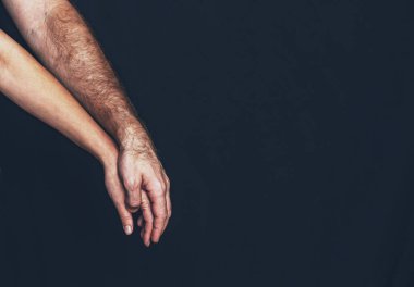 Karşılıklı destek ve bağlantı: Erkek eli yavaşça esnemiş kadın elinin üzerinde uzanan siyah arka plan, güven, empati, ortaklık, işbirliği tasvir eden