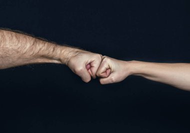 Erkek ve kadın yumruk tokuşturuyorlar. Yumruk Bump. İki yumruğun çarpışması, karşı karşıya. Saygı gösterme ya da onaylama hareketi. Dostlar selamlıyor. Takım çalışması ve arkadaşlık. Ortaklık kavramı.