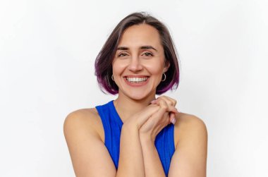 Büyük bir gülümsemeyle gülümseyen koyu renk saçlı kadın, mükemmel dişler gösteriyor. Yüze yakın eller.