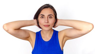 Siyah saçlı, mavi elbiseli, beyaz arka planda izole bir kadın portresi. Eller saçın yanında..