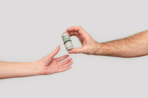 Передача долларов из рук в руки, серый фон. Концепция инвестиций, донатонов, благотворительности