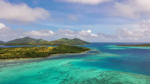 Turkuaz okyanus suları bulutların altında. Uzakta dağlar var. Fiji Adalarının İHA görüntüsü.