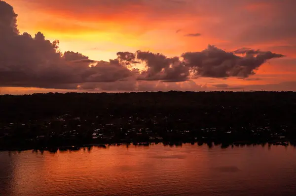 Scene of colorful sunset sky with clouds over evening city. Photo view from drone from sea.