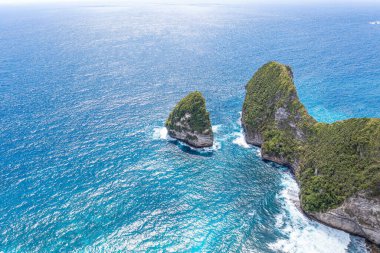 Deniz, ormanla kaplı kayalık dağlar. Suda büyük taşlar. Tatilde. Klungkung. Bali Endonezya