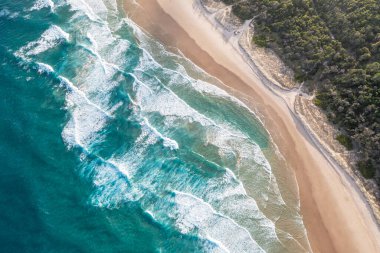 Foamy ocean waves roll and approach sandy beach. Majesty turquoise seascape. Top view from drone. clipart