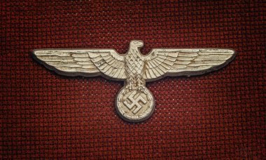 Koyu kırmızı zemin üzerinde İkinci Dünya Savaşı Alman Nazi şapka rozeti