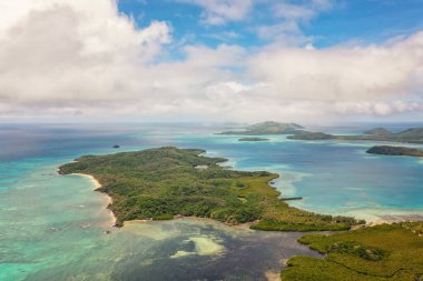 Turkuaz okyanus suları bulutların altında. Uzakta dağlar var. Fiji Adalarının İHA görüntüsü.
