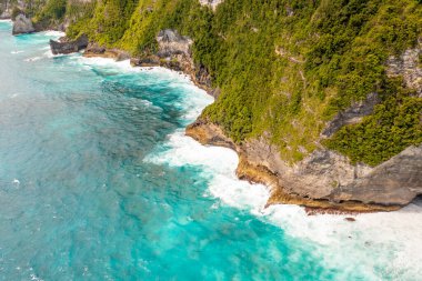 Temiz, mavi deniz, kıyıya yakın beyaz köpük. İHA görüntüsü yüksek uçurum. Bali, Klungkung, Endonezya