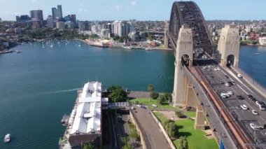 Tazman Denizi 'ndeki Sydney Kemer Köprüsü' nün panoramik görüntüsü şehrin modern binalarının arkasında..