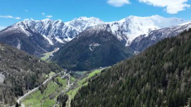 Karlı dağların manzarası, vadideki yol, İtalya 'daki Alpler. Dağlarda İHA uçuşu