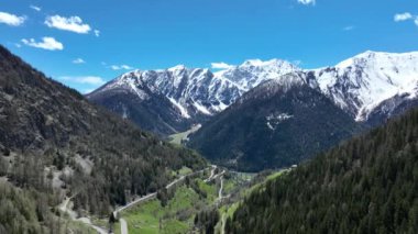Karlı dağların manzarası, vadideki yol, İtalya 'daki Alpler. Dağlarda İHA uçuşu