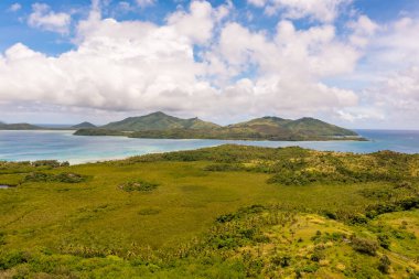Palmiye ağaçları ve beyaz kumlu açık mavi-yeşil suyu olan tropik Fiji adası. Bulutlu deniz manzarası