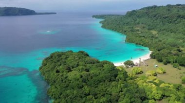 Mavi bulutların altında turkuaz deniz kıyısında yeşil kıyıların robot videosu. Tropik cennet. Sanma, Vanuatu