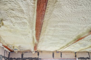Evin tavanının poliüretan köpükle izolasyonu. Tahta kirişler arasında köpük yalıtılıyor