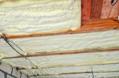 Evin tavanının poliüretan köpükle izolasyonu. Tahta kirişler arasında köpük yalıtılıyor