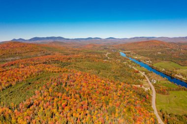 Sonbahar renkli ormanlarda mavi nehir, ufukta dağlar. New Hampshire, ABD. Drone fotoğrafı