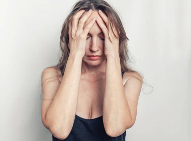 Elleriyle yüzünü kapatan kadın korku, acı ve hayal kırıklığı hisseder. Baş ağrısı kavramı