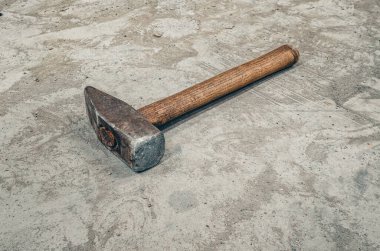 Beton zeminde eski çelik çekiç. Tahta saplı güçlü bir çekiç. Antika atölye arka planı