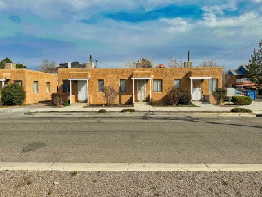 ALBUQUERQUE, New Mexico, ABD - 7 Mart 2023. Ahşap çamur evler. Ahşap pencereler ve kapılar. Evin yanındaki Bush.