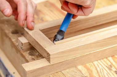 Marangoz atölyedeki tahta tahtalara bir fırçayla yapıştırıcı sürer.