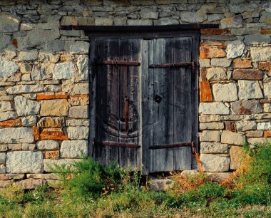 Sıkıntılı ahşap kapılı ve kırmızı kiremitli taş ahır, otantik taşra binası, taştan ve ahşaptan doğal doku, tarihi yapı