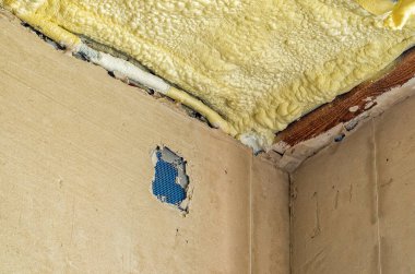 İç inşaat işi. Köpük yalıtım için tavanı kaplar. Tahta kiriş, beton duvarlar. Onarım