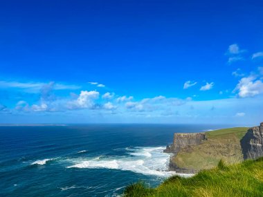 Ufkun ötesindeki engin okyanusla dramatik İrlanda kayalık kıyı şeridi, mavi sular İrlanda 'nın engebeli kıyılarıyla buluşuyor, barışçıl doğal güzellik.