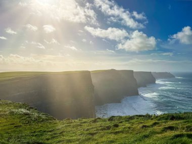 İrlanda 'nın sakin kıyı şeridi kayalık kıyı ve sonsuz mavi okyanus manzarası, engebeli doğal manzara İrlanda kıyı şeridinde ufukla buluşuyor.