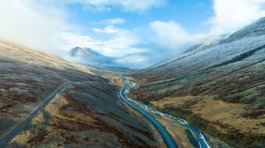 İzlanda 'daki tepeler arasında geniş nehir, kıvrımlı donmuş nehir, asfalt yol. Turist manzarası
