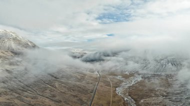 Foggy drone view of road through canyon of volcanic swamps with frozen lava and moss. Winding frozen river clipart