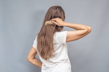 Tahta tarak. Doğal uzun saçlarla savaşıyor. Beyaz tişörtlü bir kadının dikiz manzarası. Gri arkaplan, izole