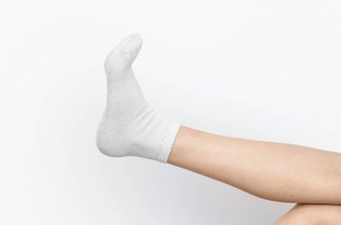 Beyaz çoraplı bir kadın bacağı. Beyaz arka plan, izole. Sıcaklık ve yumuşaklık kavramı, rahatlık.