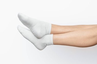 Beyaz çoraplı çapraz kadın bacakları. Beyaz arka plan, izole. Sıcaklık ve yumuşaklık kavramı, ev konforu