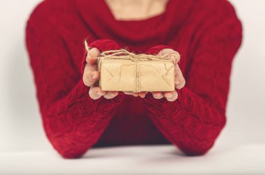 Kraft kağıdındaki hediye kırmızı kazaklı bir kadının ellerinde.