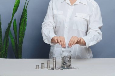 Finans ve para çarpımı kavramı. Kadın elleri cam kavanoza bozuk para atıyor. Bağış