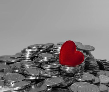 Parlak paraların üzerindeki kırmızı kalp. Gri arka plan. Sevgililer günü kartı. Tasarım için fikir