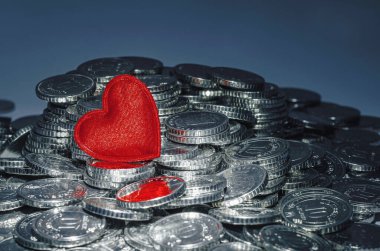 Parlak para yığınının üzerindeki kırmızı kalp. Koyu mavi arka plan. Sevgililer günü kartı. Tasarım için fikir