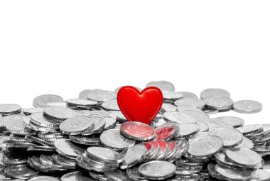 Gümüş paraların üzerindeki kırmızı makro kalp beyaza izole edilmiş. Aşk ya da para, aşk ve para. Boşluğu kopyala