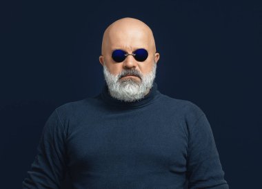 Kel sakallı adamın koyu mavi golf ve gözlüklü portresi. Matrix 'teki Morpheus' a benziyor. Siyah arkaplan