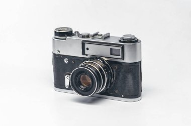 Gümüş gövdeli ve beyaz arka planda siyah derili klasik film kamerası.