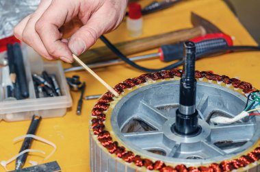 Tamir için elektrikli bisiklet motorunun yakın çekimi kaldırılıyor. Arkaplanda araçları olan tablo