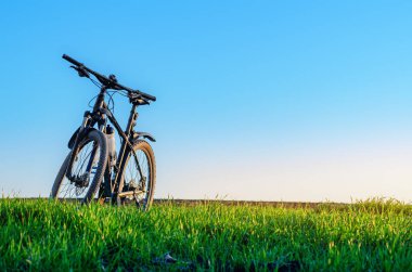 Gün batımında yeşil çimlerin üzerinde bisiklet. Ön manzara. Bisiklet konsepti. Metin iletisi eklemek için resim