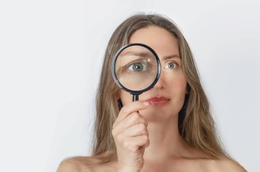 Büyüteçle kameraya bakıp gülümseyen yetişkin bir kadın. Doğrulama, seçim stratejisi kavramı