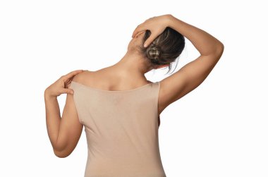 Bej gömlekli, çıplak omuzlu bir kadın boynu gevşetiyor, boyun kaslarını geriyor. Ağrıyı önlemek için başını sağa eğiyor.