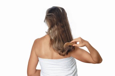 Duştan sonra kadınların dalgalı saçlarını beyaz arka planda ahşap tarakla tarıyor. Sağlıklı ve temiz saçlara dikkat et.