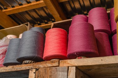 Ahşap rafta çok renkli örgü iplikleri. Çorap fabrikasında renkli iplik makaraları. Çorap üretimi