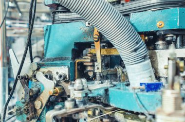 Endüstriyel örgü makinesinin egzoz borusu. Yakın plan. Örgü fabrikasının mekanizmaları. Çorap üretimi