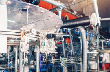 Makinelerdeki makaralarda bulunan iplik gericiler. Çorap üretimi için endüstriyel girişim